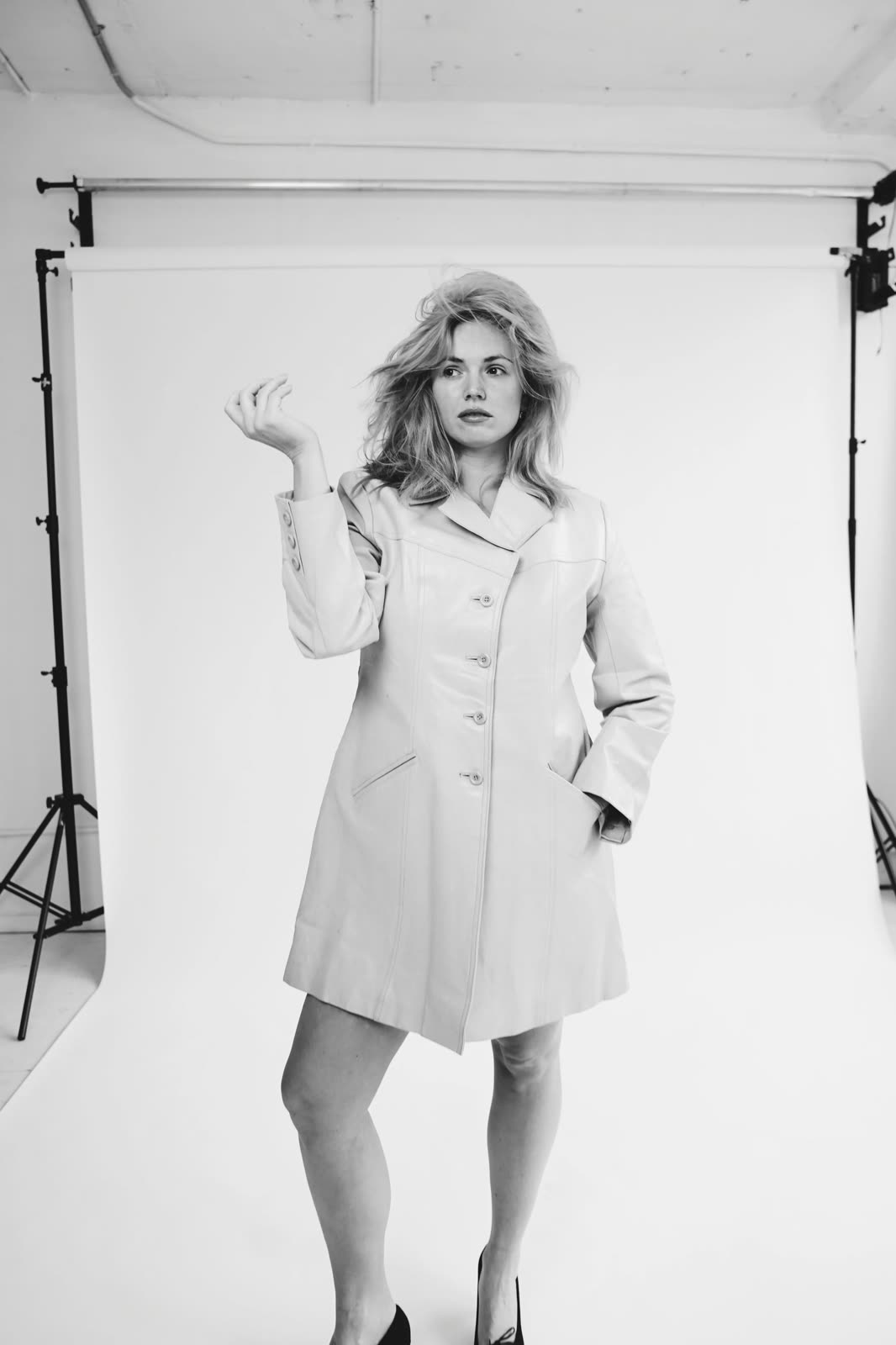 Black and white: Chloie Costello in a pale button-front coat and black heels before a paper backdrop